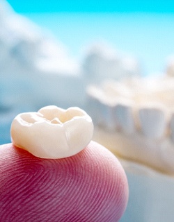 Closeup of finger holding dental crown in Mount Pleasant