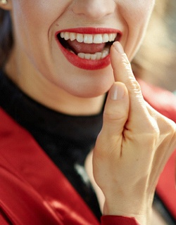 Woman smiling and pointing to dental crown in Mount Pleasant