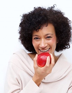 older woman eating red apple