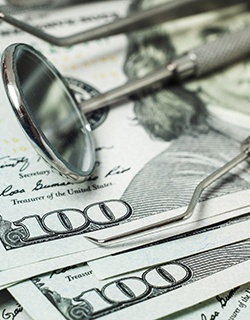 A stack of money and dental instruments lying on top of it in Mount Pleasant