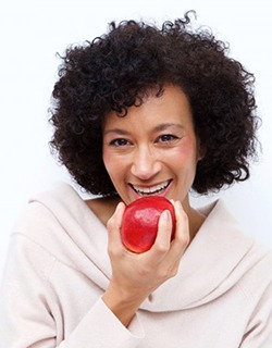 woman biting into a red apple