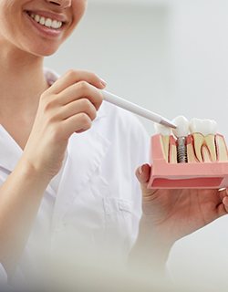 dentist showing a patient a dental implant model