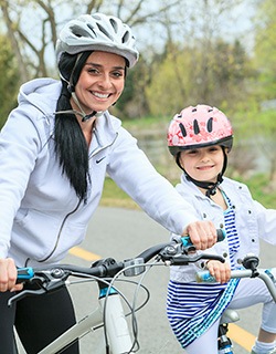 Mother and daughter smiling while riding bikes outside