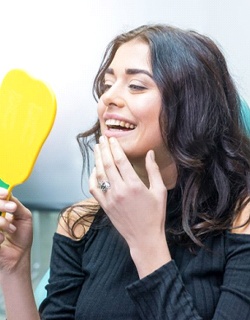 woman admiring her smile in a mirror after a smile makeover in Mount Pleasant