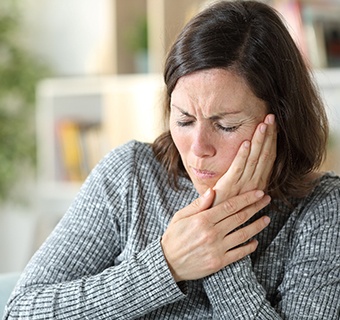 Woman rubbing jaw due to pain before TMJ therapy in Mt. Pleasant, TX