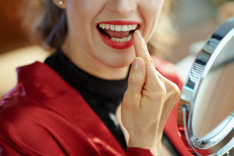 Woman checking her smile in the mirror after dental bonding