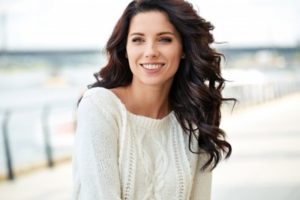 Woman with brown hair wearing a white sweater smiling